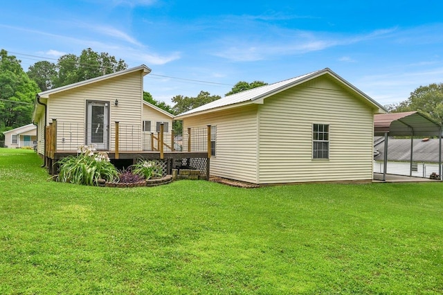 - back of property with a deck, a yard, and a carport