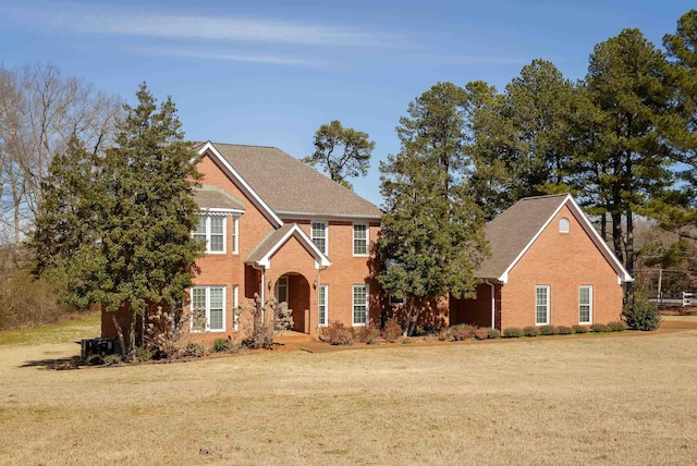 traditional-style home featuring a front yard and brick siding