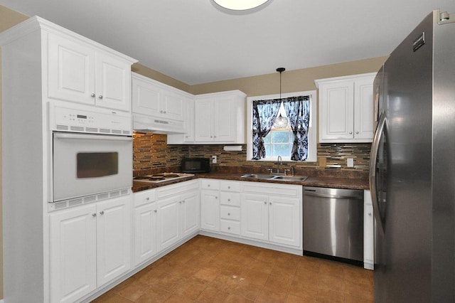  - kitchen with stainless steel appliances, under cabinet range hood, dark countertops, and backsplash