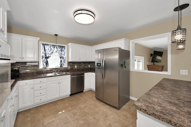  - kitchen featuring appliances with stainless steel finishes, tasteful backsplash, white cabinetry, and pendant lighting