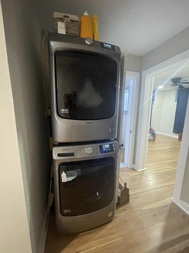 laundry area with ceiling fan, light wood-type flooring, and stacked washer and dryer