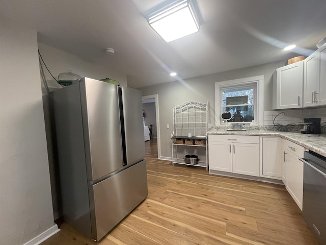 kitchen featuring light hardwood / wood-style flooring, tasteful backsplash, light stone counters, white cabinetry, and stainless steel appliances