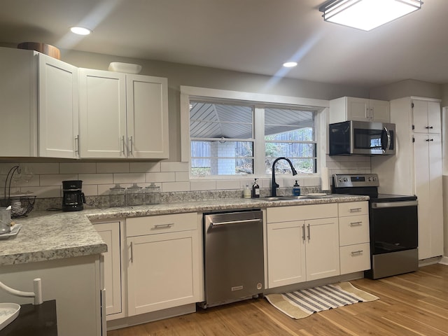 kitchen with backsplash, white cabinetry, sink, and appliances with stainless steel finishes