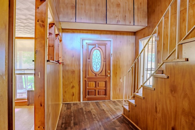 entrance foyer with wooden walls, hardwood / wood-style floors, a healthy amount of sunlight, and stairway