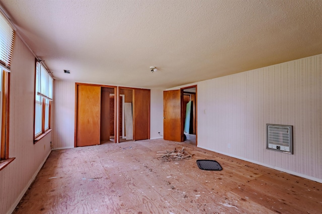 unfurnished room with baseboards, heating unit, and a textured ceiling