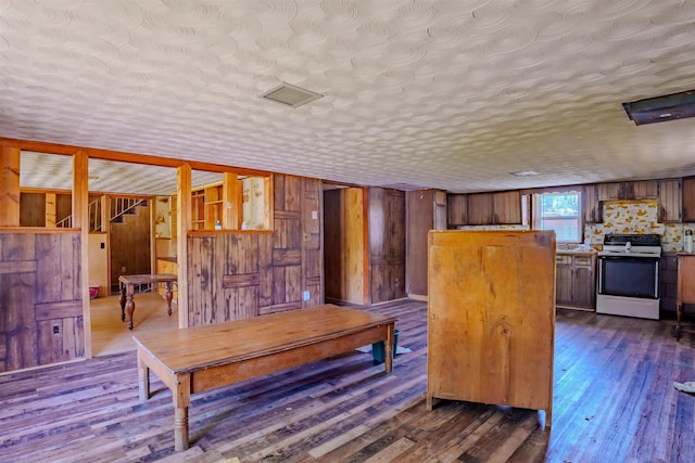 interior space with wood walls, a textured ceiling, and dark wood-style floors