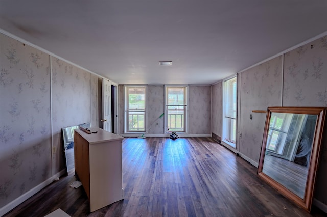 unfurnished living room featuring baseboards, dark wood-style floors, and wallpapered walls