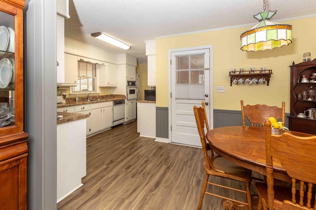 dining area with sink, dark hardwood / wood-style floors, crown molding, and a textured ceiling