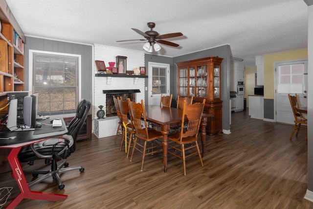 dining area featuring a fireplace, a textured ceiling, dark hardwood / wood-style floors, and ceiling fan