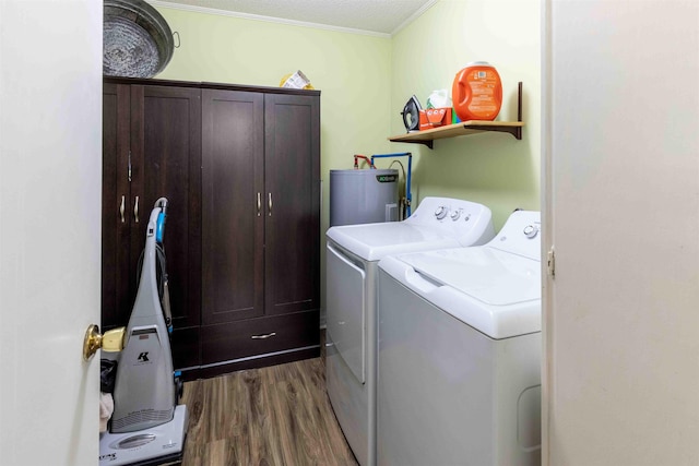 laundry area with cabinets, ornamental molding, water heater, separate washer and dryer, and hardwood / wood-style flooring