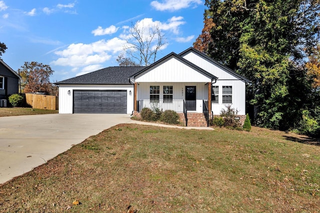 view of front of property featuring a front lawn, covered porch, and a garage