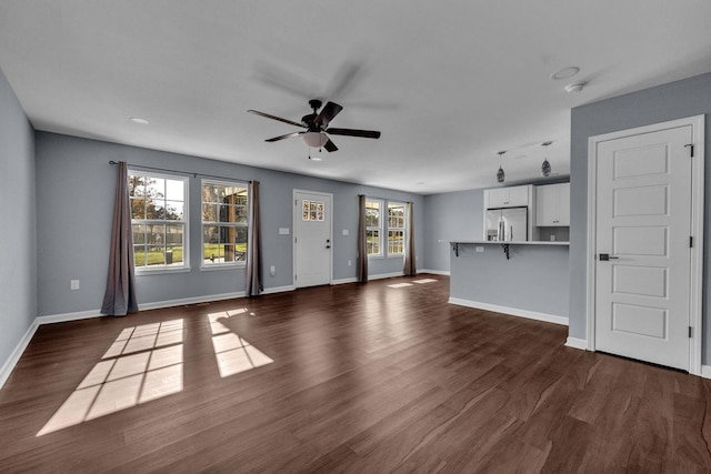 unfurnished living room with ceiling fan, dark hardwood / wood-style flooring, and a wealth of natural light