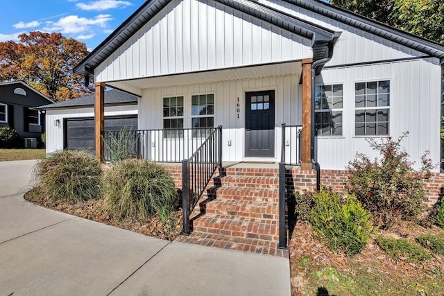 view of front facade featuring a porch, a garage, and central air condition unit