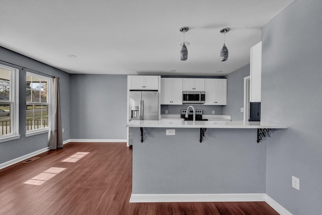 kitchen featuring kitchen peninsula, appliances with stainless steel finishes, white cabinetry, and a breakfast bar area