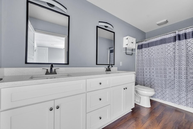 bathroom with hardwood / wood-style floors, vanity, curtained shower, and toilet