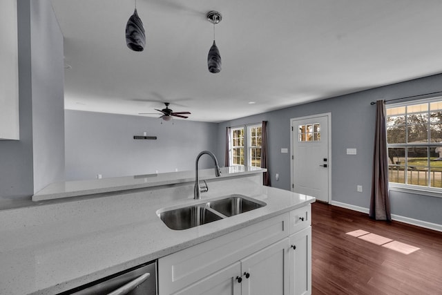 kitchen featuring white cabinets, decorative light fixtures, light stone countertops, and sink