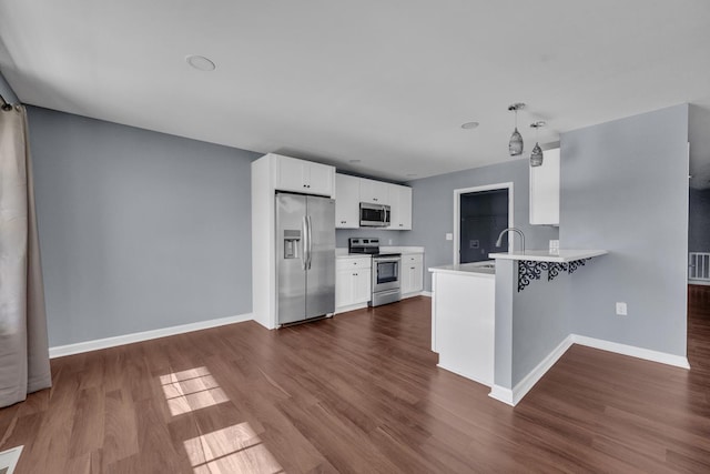 kitchen featuring kitchen peninsula, appliances with stainless steel finishes, dark hardwood / wood-style flooring, decorative light fixtures, and white cabinetry