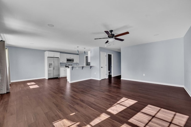 unfurnished living room featuring ceiling fan and dark wood-type flooring