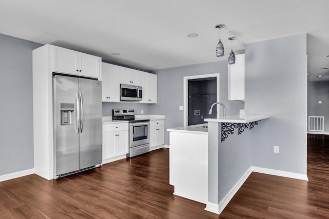 kitchen featuring dark wood-type flooring, hanging light fixtures, white cabinetry, kitchen peninsula, and stainless steel appliances