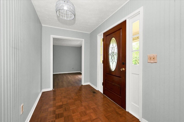  - foyer entrance with baseboards, a textured ceiling, and crown molding
