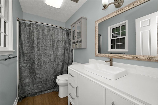  - full bath featuring wood finished floors, toilet, vanity, a textured ceiling, and a shower with curtain