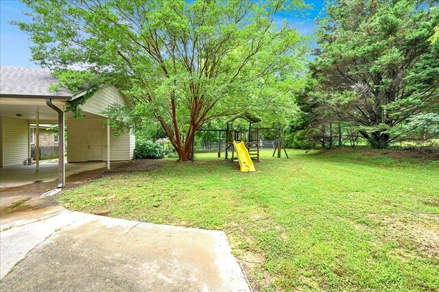  - view of yard featuring a playground, a carport, and concrete driveway