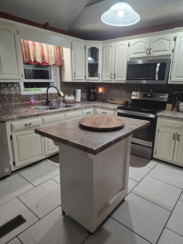 kitchen featuring sink, stainless steel appliances, white cabinets, a kitchen island, and decorative backsplash