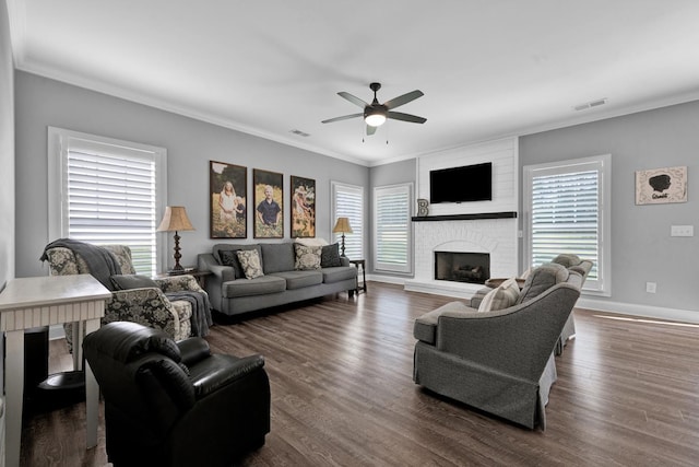 living room featuring ceiling fan, crown molding, dark wood-type flooring, and a brick fireplace