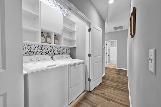 laundry area with washer and clothes dryer and light hardwood / wood-style floors