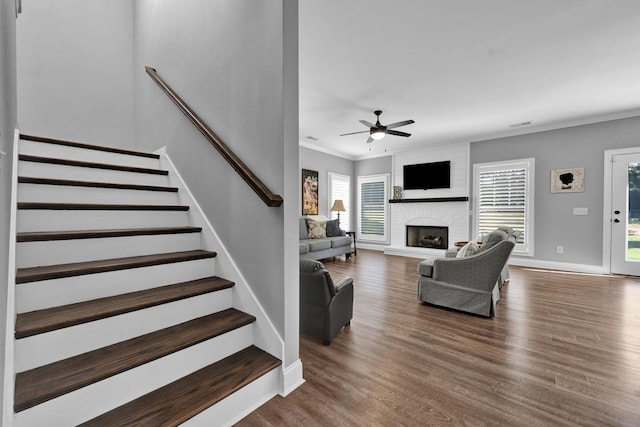 living room featuring ceiling fan, dark hardwood / wood-style flooring, a wealth of natural light, and a brick fireplace