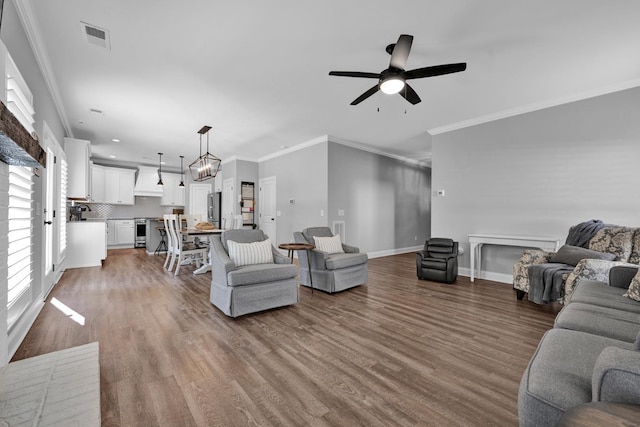 living room featuring crown molding, wood-type flooring, and ceiling fan with notable chandelier