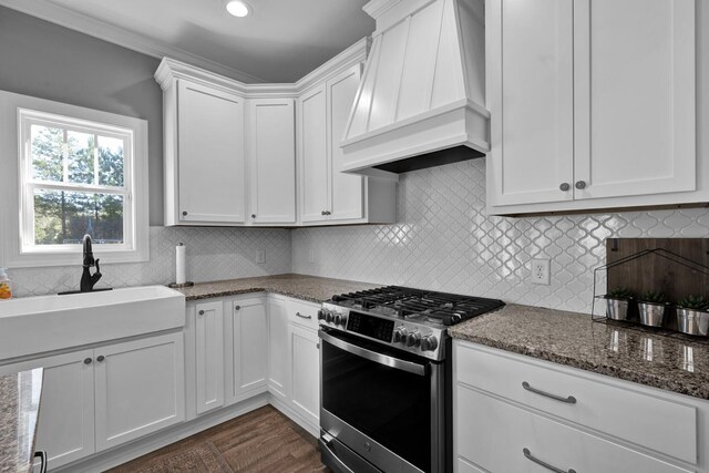 kitchen featuring gas range, stone counters, sink, premium range hood, and white cabinets