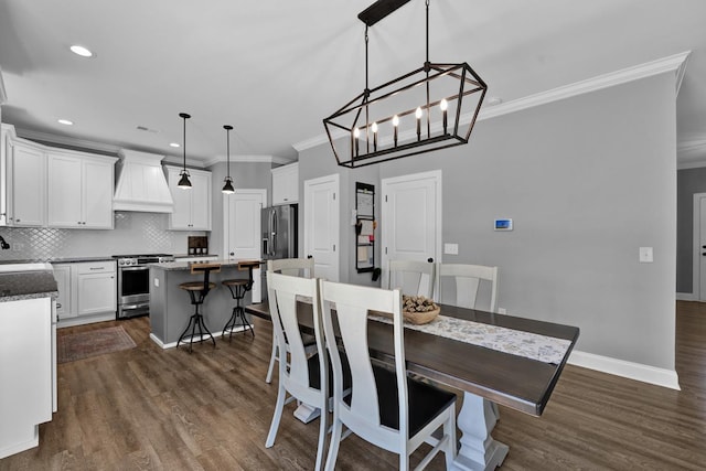 dining area with sink, dark hardwood / wood-style flooring, a notable chandelier, and ornamental molding