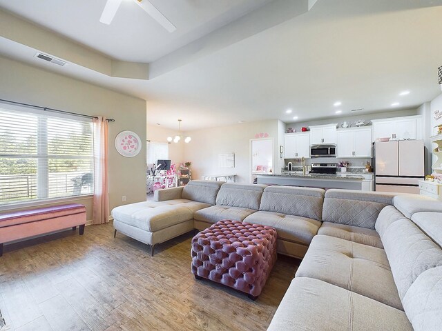 living room with ceiling fan with notable chandelier and hardwood / wood-style flooring