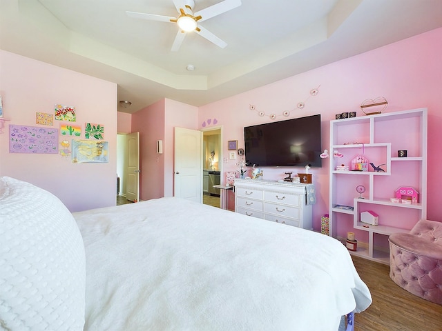 bedroom with ceiling fan, a raised ceiling, and dark wood-type flooring