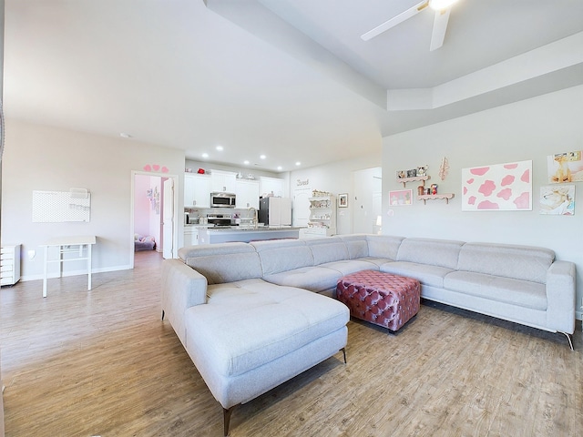 living room featuring light hardwood / wood-style flooring, ceiling fan, and sink