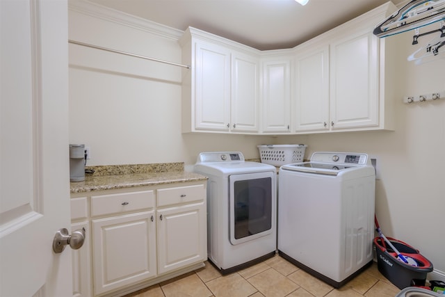 clothes washing area featuring cabinets, washer and clothes dryer, and light tile patterned flooring