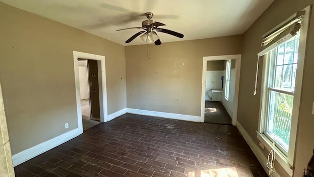 unfurnished room featuring a wealth of natural light, ceiling fan, and baseboards