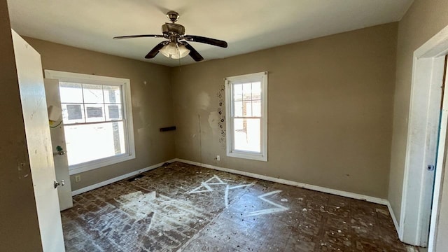 empty room featuring a ceiling fan and baseboards