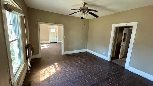 unfurnished room with dark wood-style floors, visible vents, ceiling fan, and baseboards