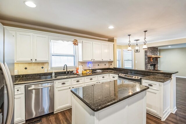 kitchen with a center island, sink, stainless steel appliances, pendant lighting, and white cabinets