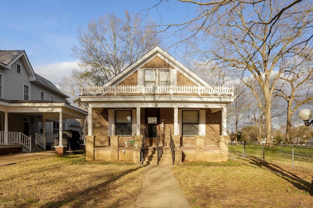 view of front of home with covered porch, brick siding, fence, and a front lawn