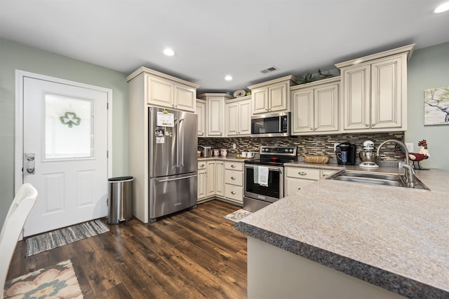 kitchen featuring cream cabinets, a sink, visible vents, appliances with stainless steel finishes, and dark wood finished floors