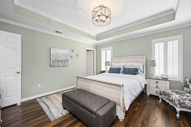 bedroom with a tray ceiling, hardwood / wood-style flooring, visible vents, and baseboards