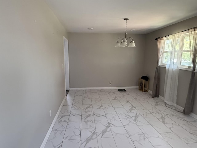 spare room with baseboards, marble finish floor, and a chandelier