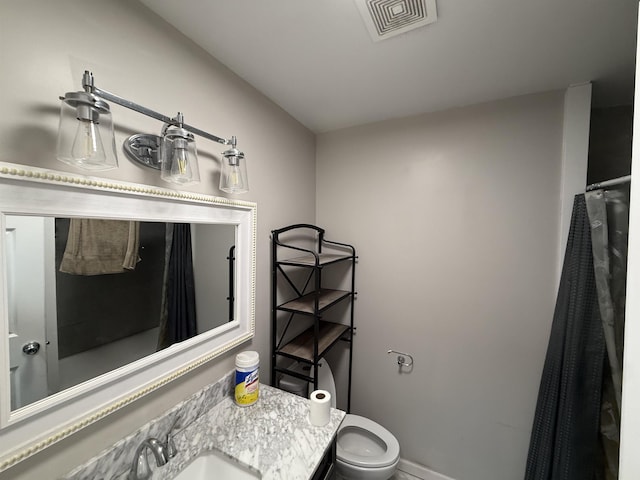 bathroom with toilet, vanity, visible vents, and baseboards