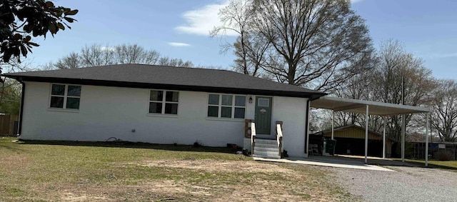 ranch-style house with a carport, gravel driveway, brick siding, and a front yard