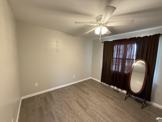 unfurnished room featuring baseboards, a ceiling fan, visible vents, and dark wood-style floors