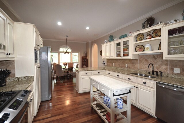 kitchen featuring a sink, open shelves, a peninsula, stainless steel appliances, and ornamental molding
