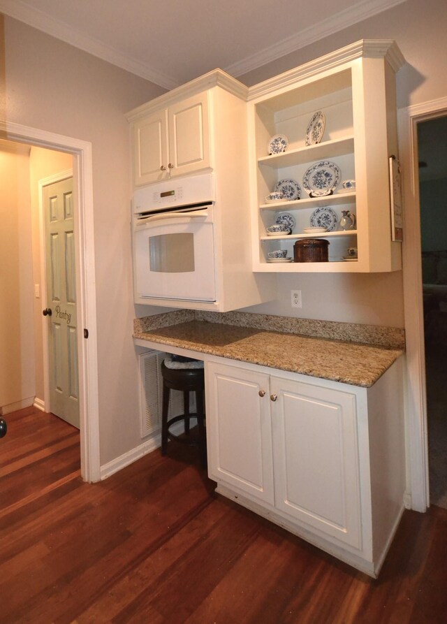 kitchen featuring white oven, open shelves, white cabinetry, dark wood-type flooring, and ornamental molding